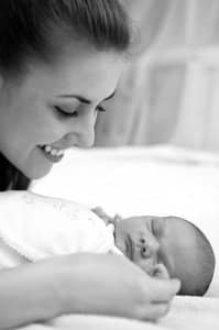 A mother looking over her newborn baby smiling