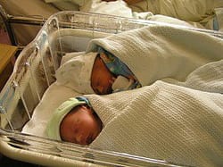 infant babies sleeping in a baby bed next to mother