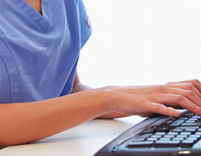 Health care worker typing on a computer keyboard
