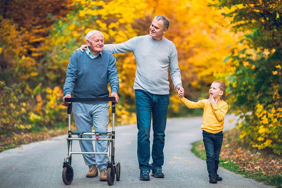 A father and young son walking outside on a trail with their grandfather
