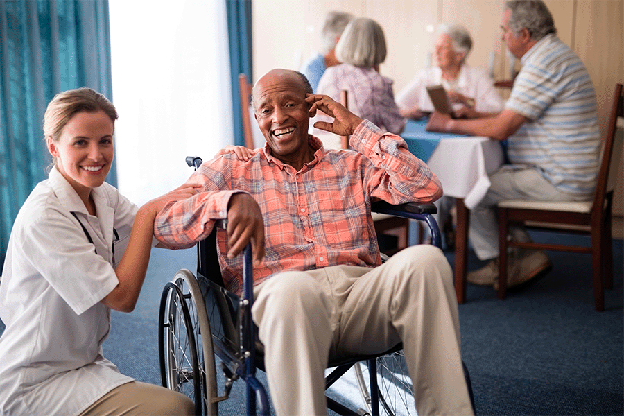 A healthcare worker and patient smiling while at the nursing home.