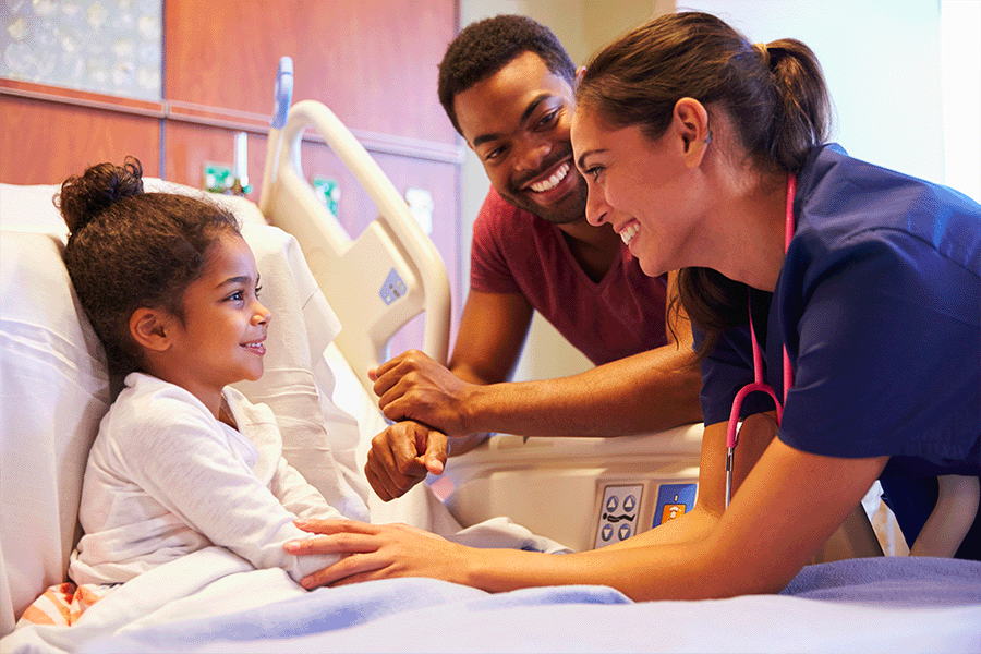 A young girl patient and her father smiling at her nurse.